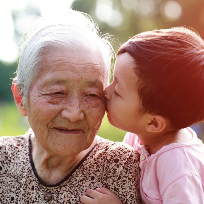 Senior Asian woman receiving a kiss on the cheek from her great grandchild