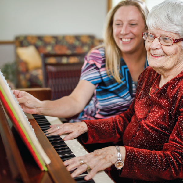 senior woman and grand daughter playing piano